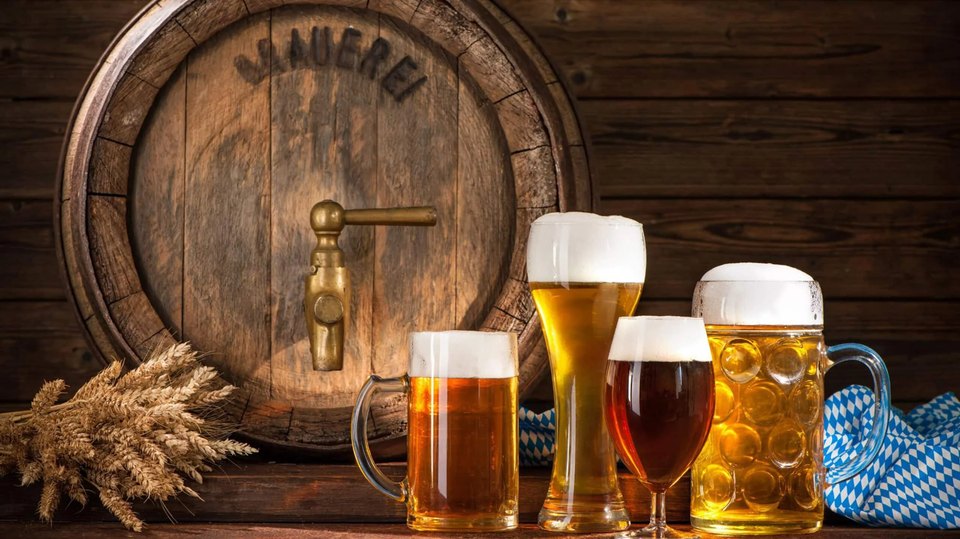 Glasses of beer in front of a wooden keg