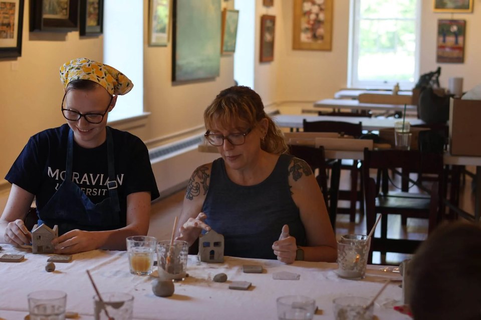 Two women making handcrafted pottery tealight holders during a craft retreat in Bethlehem, PA