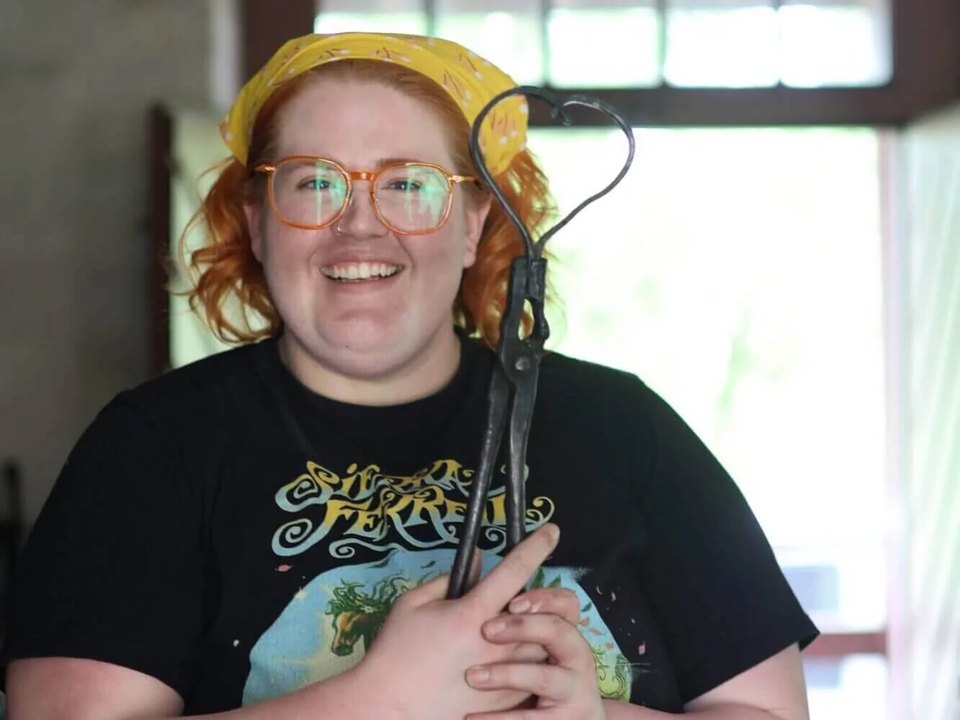 A woman who attended the Maker's Retreat in Historic Bethlehem holds an iron heart craft she created during a beginner blacksmithing workshop