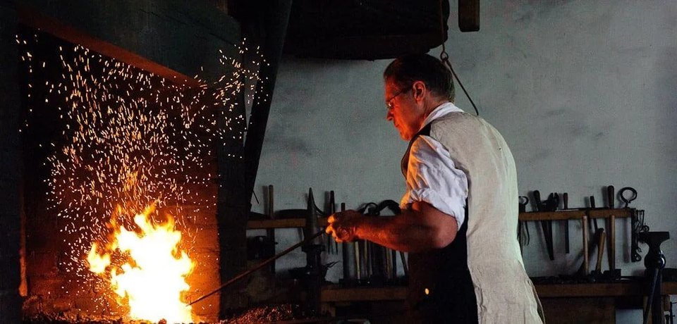Black smith heating metal item up in a fire